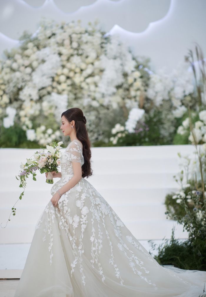 Cận cảnh nhan sắc của cô dâu Midu trong ngày trọng đại. Nữ diễn viên diện mẫu đầm dáng xòe bồng bềnh, đính hoa đẹp mắt, phần cổ thiết kế gợi cảm. 