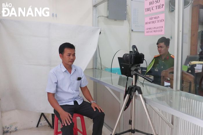 Người dân được cán bộ công an hướng dẫn đăng ký căn cước qua VNeID, sau đó lấy phiếu chờ tới lượt.