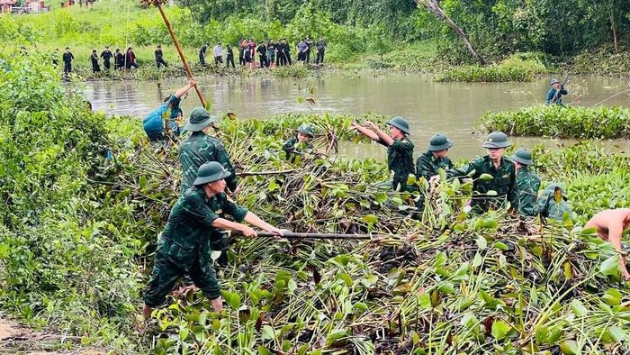 Bộ đội Biên phòng thành phố giúp dân nạo vét, xử lý bèo, khơi thông lối thoát nước. Ảnh: DOÃN QUANG