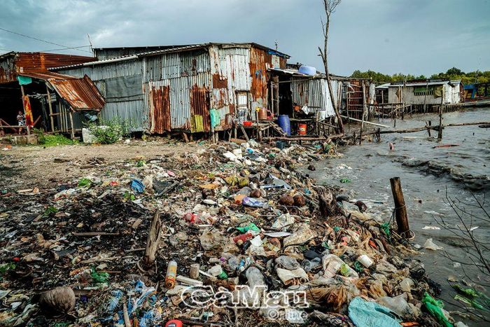 Rác sinh hoạt tấp vào các ngôi nhà tạm bợ ngoài cửa biển, tạo thành bãi vây kín nhà dân.