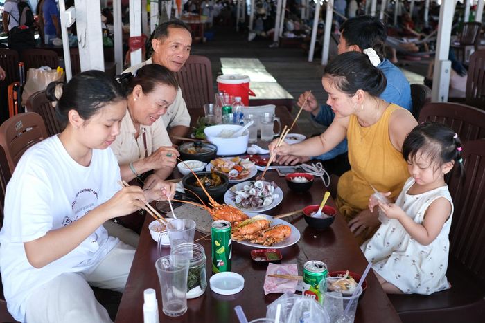  Gia đình du khách đến từ Đồng Nai thưởng thức bữa trưa trên nhà bè. Ảnh: Hoàng Trang.