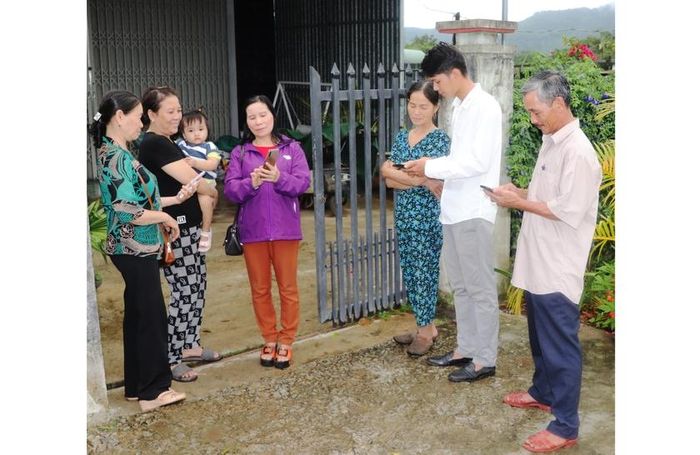 Bà Phạm Thị Thú (bìa trái) cùng cán bộ tổ dân phố 4 tuyên truyền, hướng dẫn người dân tham gia nhóm Zalo để cập nhật các thông tin của tổ. Ảnh: N.M