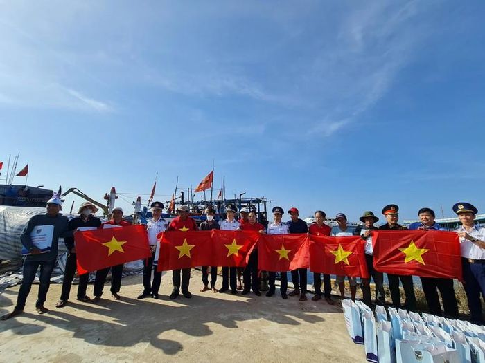 Lãnh đạo các đơn vị Cảnh sát biển, Bộ đội Biên phòng thăm, tặng cờ Tổ quốc cho các ngư dân đang neo đậu tàu thuyền tại Cảng An Hải, huyện Lý Sơn - Ảnh: VGP/Hải Định
