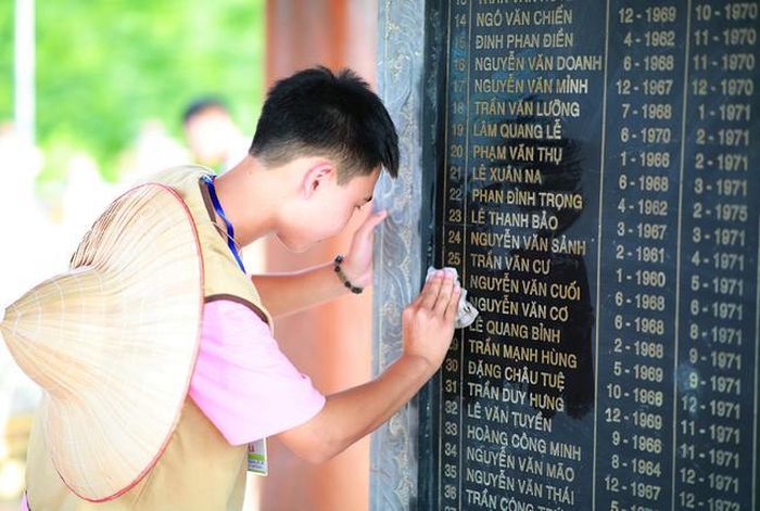 Một bạn trẻ đang chăm sóc bia tưởng niệm trong nghĩa trang liệt sĩ tại Ninh Bình. Ảnh: Lương Đình Khoa