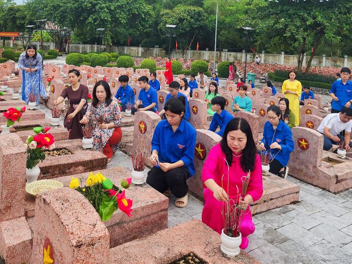 GIáo viên, học sinh Trường THPT Nguyễn Duy Trinh thắp hương cho các phần mộ liệt sĩ tại Nghĩa trang Liệt sĩ huyện Nghi Lộc. Ảnh: CSCC