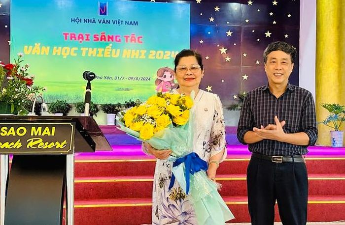 Nhà văn Nguyễn Bình Phương tặng hoa cho đại diện resort Sao Mai, nơi hỗ trợ ăn ở miễn phí cho trại sáng tác văn học thiếu nhi