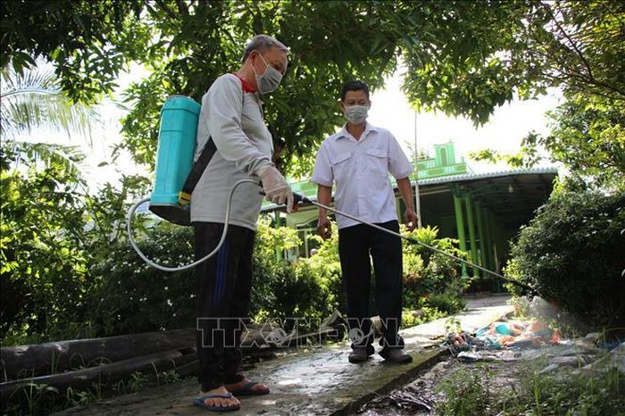 Cán bộ hướng dẫn người dân phun thuốc khử trùng chuồng nuôi.