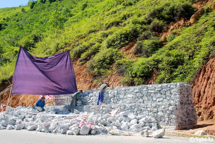 Tại khu vực dốc Dài, thuộc bản Vẽ, xã Yên Na cũng đang được tiến hành kè rọ đá tại điểm sạt lở. Điểm này có chiều dài khoảng 70 mét. Do thời tiết nắng nóng, người dân phải căng bạt ra để làm việc. Ảnh: Xuân Hoàng