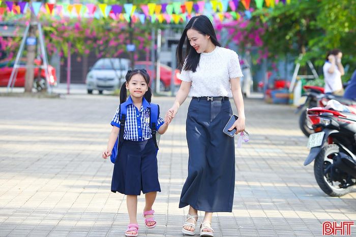  Các bạn nhỏ lớp 1 tới trường trong vòng tay của bố mẹ. 