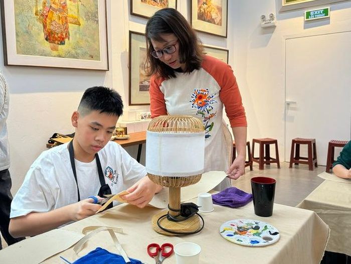 Chị Nguyễn Thị Hữu hướng dẫn bạn nhỏ hoàn thiện chiếc lồng đèn