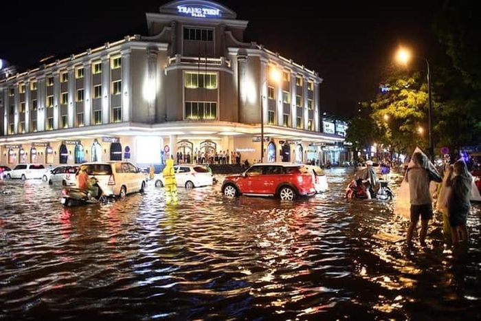 Sau cơn mưa nhưng nước vẫn chưa kịp rút, người và phương tiện di chuyển khó khăn tại khu vực Tràng Tiền.