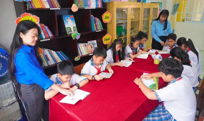  Giáo viên quan tâm hỗ trợ học sinh đọc sách tại tủ sách trong dịp hè. 
