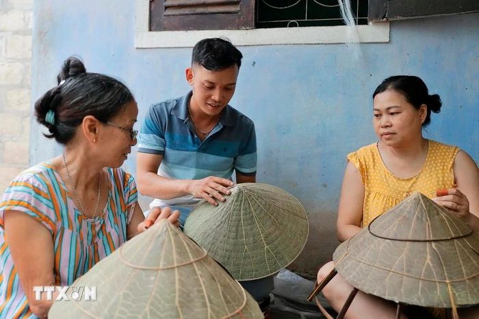  Anh Nguyễn Thanh Thảo trao đổi với những người thợ làng nón truyền thống Đốc Sơ (Huế) về sản phẩm nón sen. (Ảnh: Minh Quyết/TTXVN) 