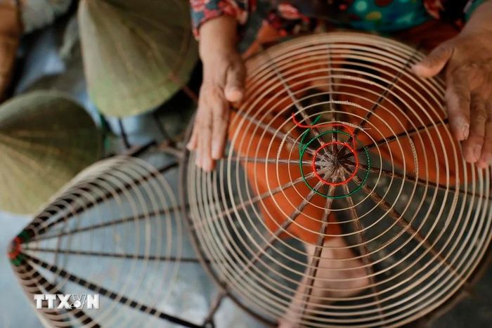  Người thợ chằm nón Làng nón Đốc Sơ (phường Hương Sơ, thành phố Huế) chuẩn bị nan tre được vót nhỏ uốn quanh khung hình chóp trước khi chằm nón. (Ảnh: Minh Quyết/TTXVN) 