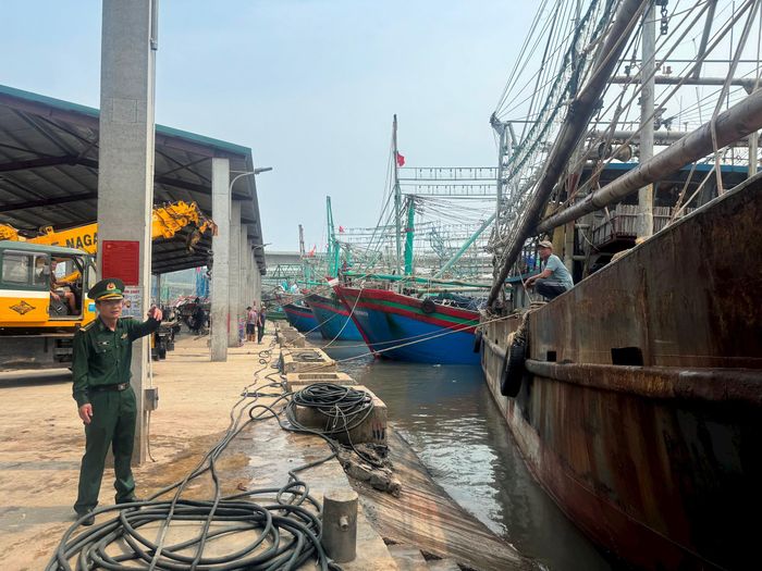 Cán bộ Trạm Biên phòng cảng Lạch Quèn, thuộc Đồn Biên phòng Quỳnh Thuận nhắc nhở 1 chủ tàu vào neo đậu tại bờ Bắc cảng Lạch Quèn chưa sơn sửa lại biển kiểm soát tàu sau khi chuyển nhượng. Ảnh: Nguyễn Hải