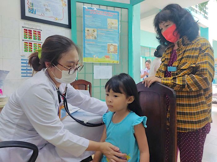  BS Phạm Vân Thảo, Phó trưởng trạm y tế phường Tân Thành, Tân Phú thăm khám cho trẻ trước khi tiêm. Ảnh: QUANG HUY 
