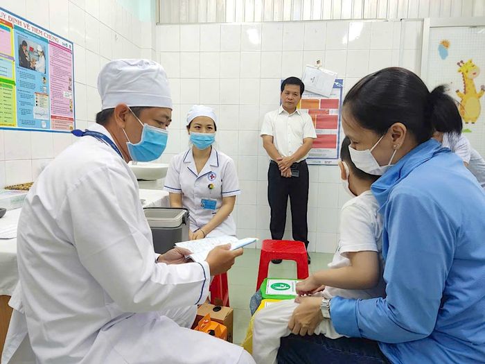  BS-CKII Nguyễn Hồng Tâm, Giám đốc Trung tâm Kiểm soát bệnh tật TPHCM (HCDC) - chính giữa hình, giám sát công tác tiêm chủng cho trẻ tại trạm y tế phường Tân Thới Hòa, Tân Phú. Ảnh: QUANG HUY 