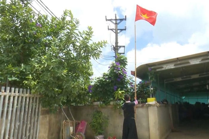 Anh Giàng A Phư treo cờ Tổ quốc để đón Tết Độc lập. Ảnh: Ái Vân