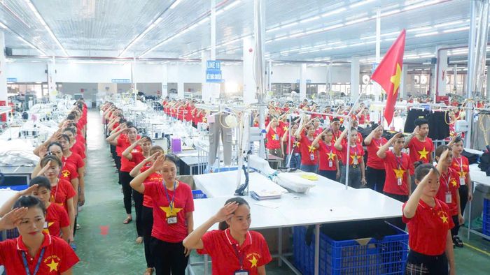 Lễ chào cờ trong màu áo cờ đỏ sao vàng tại một xưởng may tại Tân Kỳ. Ảnh tư liệu: CSCC