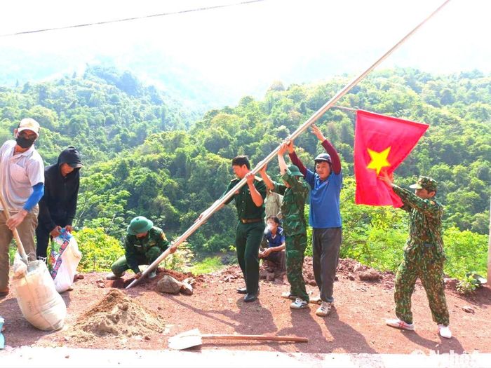 Trên mỗi cột điện chiếu sáng đường bản do Đồn Biên phòng Mỹ Lý hỗ trợ lắp đặt đều có gắn cờ Tổ quốc. Ảnh: K.L