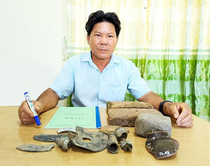 Ông Bùi Phích-Chủ tịch UBND xã Đăk Hlơ và một số hiện vật mới được tìm thấy ở di tích Tân Lập. Ảnh: N.Q.T