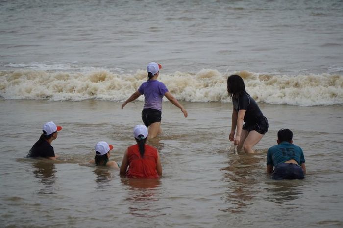 Có rất nhiều phụ nữ xuống tắm biển trong khi trời đã bắt đầu mưa, sóng biển dâng cao
