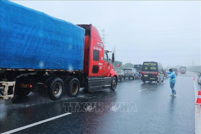 Nhân viên Công ty BOT Pháp Vân - Cầu Giẽ hướng dẫn các phương tiện đi sang bên trái, tránh vùng ngập sâu bên phải tại đoạn Km 191 + 500 trên cao tốc Pháp Vân - Cầu Giẽ (ảnh chụp lúc 10h25 ngày 11/9). Ảnh: Hoàng Hiếu/TTXVN