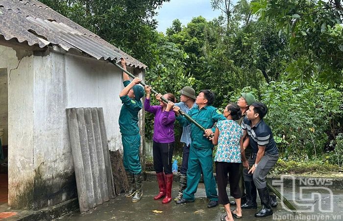Lực lượng chức năng xã Vạn Phái (TP. Phổ Yên) hỗ trợ người dân lợp lại mái nhà.
