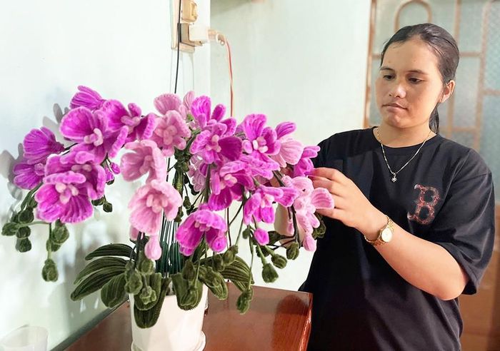 Chị H'Thoi tự đan móc những bông hoa bằng len để trang trí phòng khách của gia đình. Ảnh: P.D