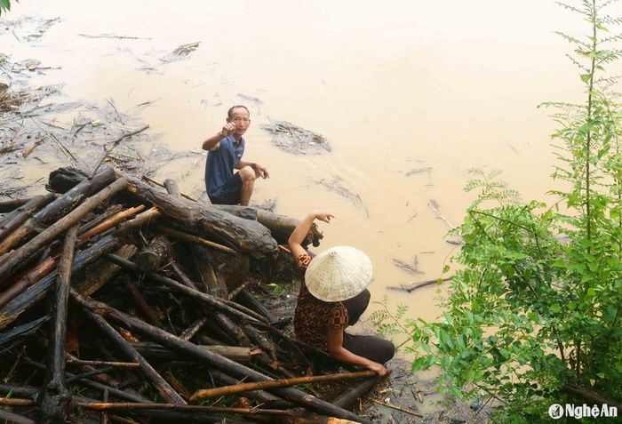 Theo người dân địa phương, ngày thường vực Quánh đã khá nguy hiểm, ngày mưa lũ nước sông Lam dâng cao, chảy xoáy dưới chân núi Quánh càng nguy hiểm hơn. Người dân đi vớt củi ngồi trên vỉa đá ven bờ sông chờ củi. Ảnh: Huy Thư