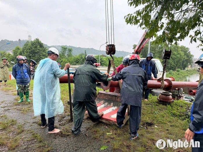 Công ty CP Hạ tầng Đầu tư và Phát triển đô thị Vinh phải dùng máy cơ giới kê kích đường ống để bơm cưỡng bức qua đường ven sông Lam (Quốc lộ 46C). Ảnh: Nguyễn Hải