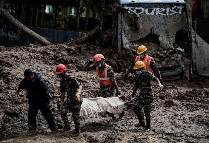  Lực lượng cứu hộ đưa thi thể nạn nhân ra khỏi một xe buýt bị chôn vùi. Ảnh: Reuters/Navesh Chitrakar.