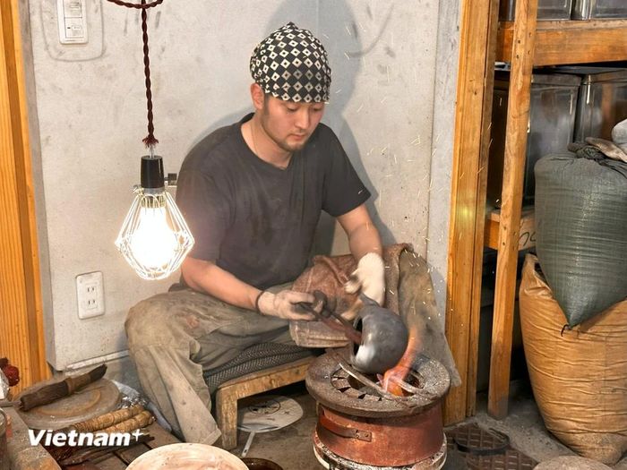 Một người thợ trẻ đang thực hiện những công đoạn cuối để sản xuất ra một chiếc ấm Akai Rigon. (Ảnh: Nguyễn Tuyến-Xuân Giao-Phạm Tuân/Vietnam+)