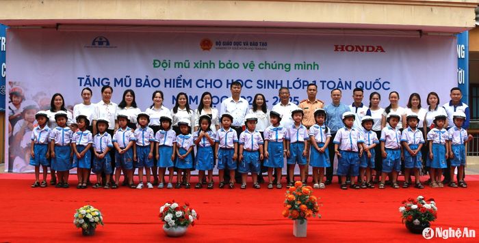 Đại diện Ban tổ chức chương trình trao tặng mũ bảo hiểm cho các em học sinh tại Trường Tiểu học Hưng Dũng 1. Ảnh: Đ.C