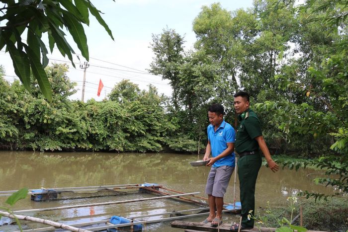 Đại úy Lê Văn Hải thường xuyên tới nhà trao đổi, hướng dẫn anh Nguyễn Văn Đức chăm sóc cá. Ảnh: Bích Nguyên