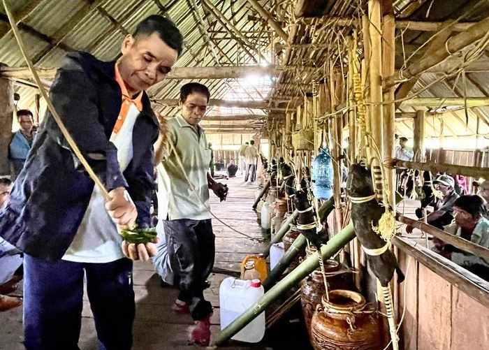  Già làng A Hing cho hay việc lấy một ít rượu từ các ghè rượu vào chiếc phễu chung thể hiện tình đoàn kết của các hộ dân trong làng, trên dưới đồng lòng. Ảnh: M.N