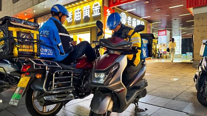 Những người giao đồ ăn đang ngồi trên xe để nhận đơn hàng tiếp theo vào tháng 10-2024 tại Trùng Khánh (Trung Quốc). Ảnh: Cheng Xin/Getty Images