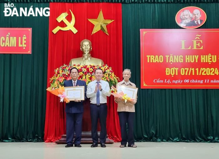 Bí thư Quận ủy Nguyễn Văn Hùng (giữa) trao Huy hiệu Đảng cho các đảng viên. Ảnh PV