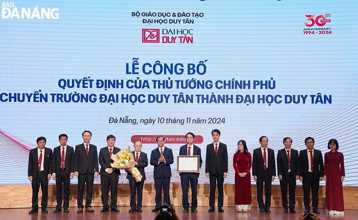 Bộ trưởng Bộ Giáo dục và Đào tạo Nguyễn Kim Sơn (thứ 6 từ trái sang) trao quyết định của Thủ tướng Chính phủ chuyển Trường Đại học Duy Tân thành Đại học Duy Tân. Ảnh: THU HÀ.