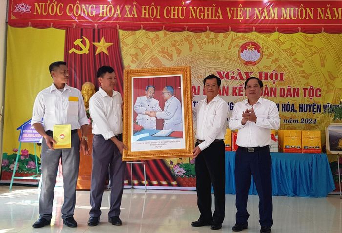 Ông Nguyễn Quang Hải, Phó Chủ tịch HĐND và ông Võ Minh Khoa, Phó Chủ tịch Ủy ban MTTQ tỉnh Thanh Hóa trao tặng nhân dân thôn Quang Biểu bức ảnh Bác Hồ - Bác Tôn tại Ngày hội.