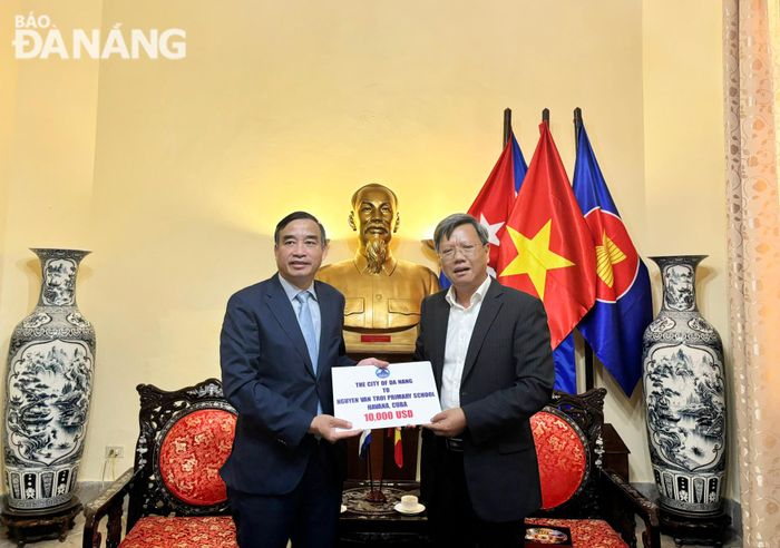 Chủ tịch UBND thành phố Lê Trung Chinh (bên trái) trao hỗ trợ cho Trường Tiểu học Nguyễn Văn Trỗi tại Cuba thông qua Đại sứ quán Việt Nam tại Cuba.