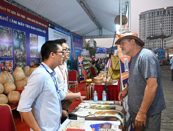 Du khách nước ngoài rất thích thú trước gian hàng sản phẩm làm từ tranh Đông Hồ.