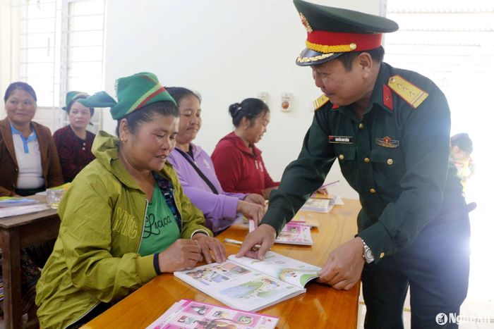 Cán bộ Đoàn Kinh tế - Quốc phòng 4 hướng dẫn, động viên người dân xã Tri Lễ học xóa mù chữ. Ảnh: Tiến Hùng