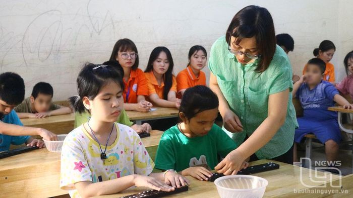 Cô giáo Trần Thị Vân Anh hướng dẫn cho học sinh khiếm thị đọc bài tại lớp.