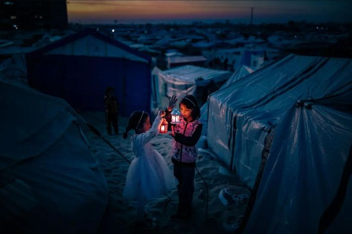  Trẻ em Palestine ở khu vực tị nạn tại Tel al-Sultan trang trí lều trại bằng đèn lồng trước tháng lễ Ramadan linh thiêng của người Hồi giáo ở Rafah, Gaza, vào ngày 29/2. Theo giới chức Palestine, hơn 16.700 trẻ em thiệt mạng trong cuộc tấn công của Israel vào Gaza kể từ tháng 10/2023, chiếm hơn 30% tổng số 43.341 người tử vong được các cơ quan y tế xác nhận. Ảnh: Belal Khaled—Anadolu/Getty Images 