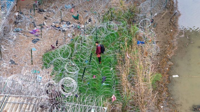  Một người nhập cư đứng trước với những cuộn dây thép gai sau khi vượt sông Rio Grande từ Mexico tại Eagle Pass, Texas, ngày 17/3/2024. Theo một báo cáo mà New York Post thu thập được, số lượng người nước ngoài có mục tiêu tiến vào biên giới phía nam của Mỹ đã tăng vọt dưới thời chính quyền Biden - Harris, với khoảng 1,7 triệu người. Hàng triệu người nhập cư không có giấy tờ hợp pháp tại Mỹ đang đối mặt với một tương lai bất định khi Tổng thống đắc cử Donald Trump tuyên bố thực hiện các biện pháp mạnh tay đối với vấn đề nhập cư. Kế hoạch này bao gồm việc ban bố tình trạng khẩn cấp quốc gia và sử dụng quân đội để trục xuất hàng loạt người nhập cư trái phép. Ảnh: John Moore - Getty Images. 