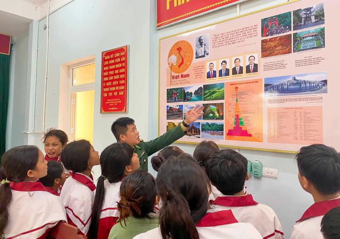 Cán bộ Đồn biên phòng Cửa khẩu quốc tế La Lay giới thiệu cho các em học sinh và thầy, cô giáo về truyền thống 80 năm Ngày thành lập Quân đội nhân dân Việt Nam, 35 năm Ngày Hội Quốc phòng toàn dân. (Ảnh: Văn Tám)