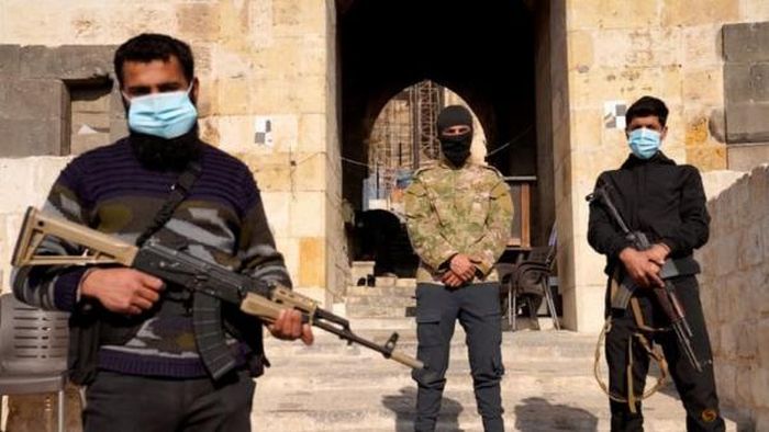 Các tay súng canh gác bên ngoài một tòa nhà ở Aleppo (Syria) ngày 9/12. Ảnh: Reuters