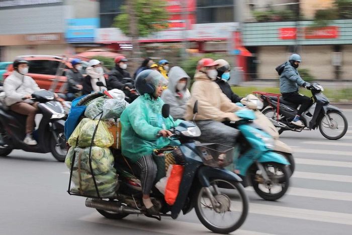Để chống lại cái lạnh, ngoài mặc đồ ấm, người lao động, buôn bán ngoài trời còn mặc thêm áo mưa để chống mưa, rét. (Ảnh: Hoàng Hiếu/TTXVN)