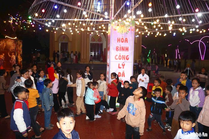 Cây thông 3 tầng độc đáo như lan tỏa hơn niềm vui đón Giáng sinh của bà con trong giáo xứ. Trẻ em thích thú khi được vui chơi dưới cây thông "khủng". Ảnh: Huy Thư